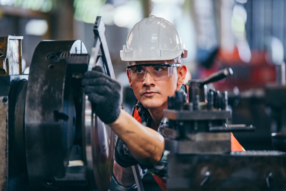 Manufacturing technician in a hard hat and safety glasses operating equipment